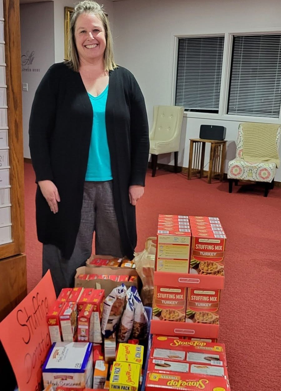 Volunteer beside stacks of donated stuffing mix boxes